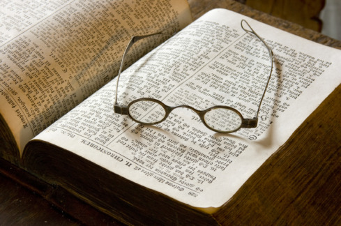 Ett par gamla glasögon på en uppslagen bok.