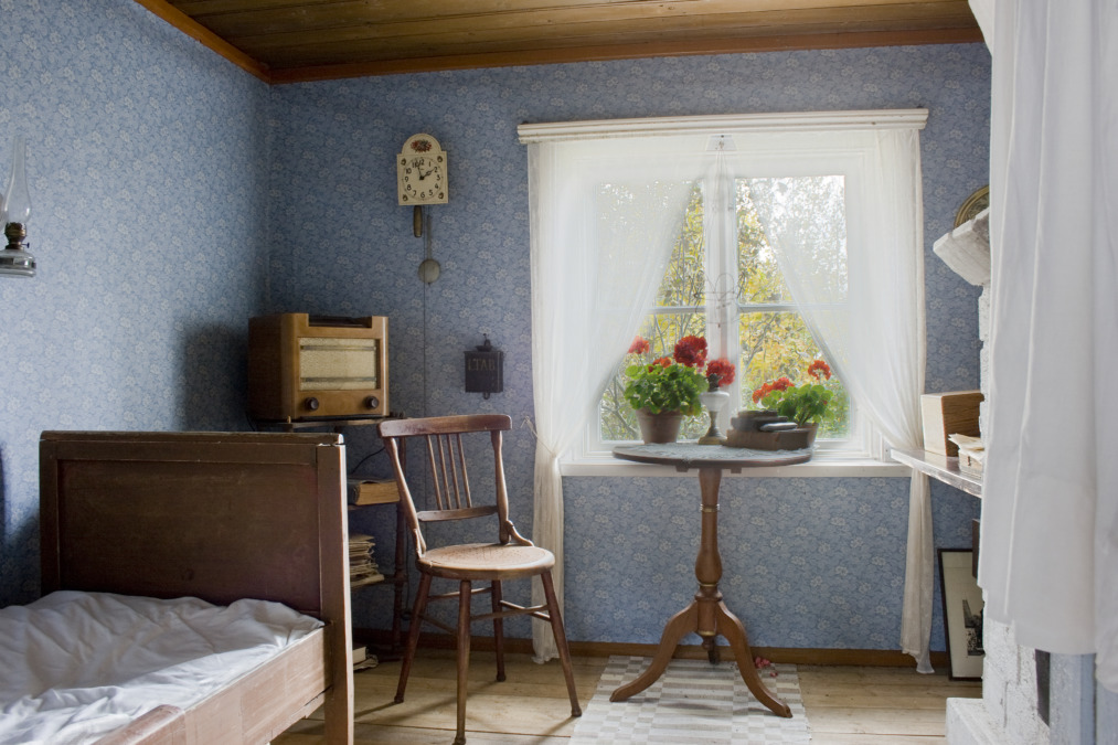 Ett gammaldags sovrum med blåa blommiga tapeter och möbler i trä på Malmtorp bondgårdsmuseum.