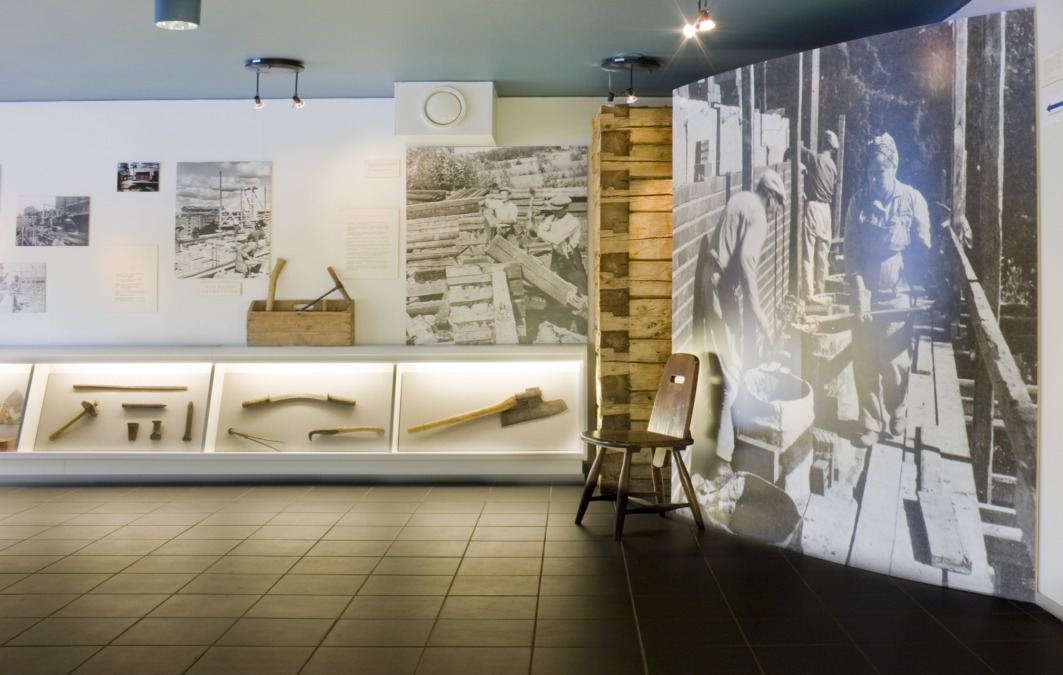 Rakennusalan työvälinemuseon näyttely, jossa esillä on työkaluja, salvottu hirsinurkka ja valokuvia rakennustyömailta.
