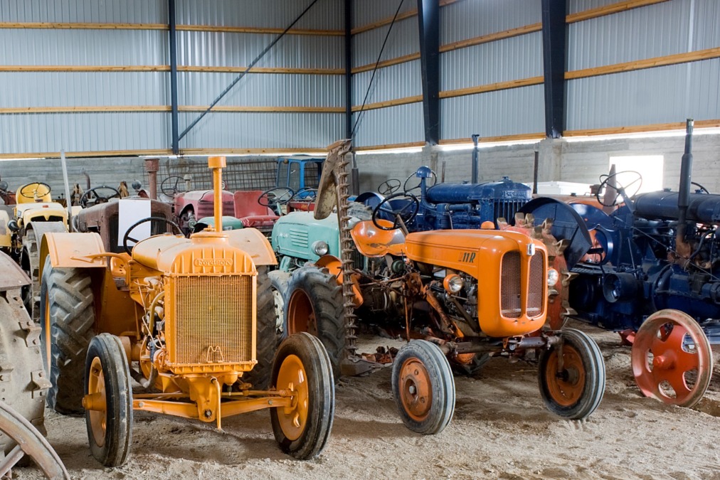 Erivärisiä ja mallisia traktoreita riveissä Kovelan traktorimuseon hallissa.